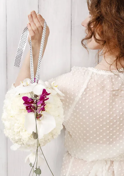 Mujer joven sosteniendo una bola de pomandro de boda hecha de flor blanca — Foto de Stock