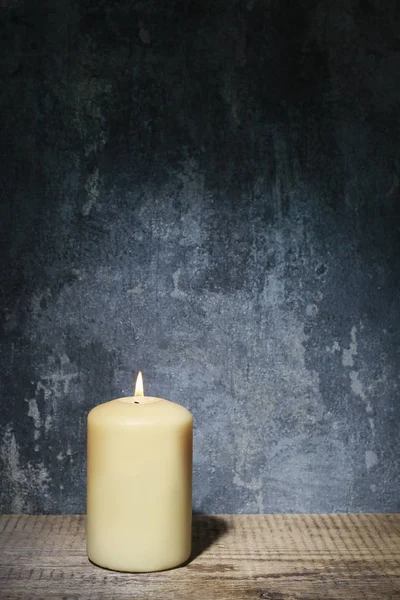 Candela singola e illuminazione drammatica su sfondo grigio in pietra — Foto Stock