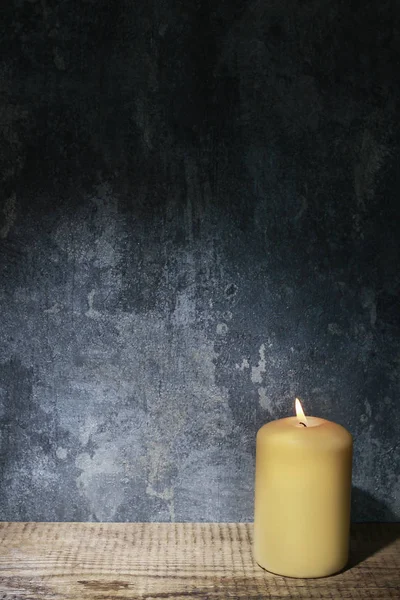 Pojedyncza świeca i dramatyczne oświetlenie na szarym tle kamienia — Zdjęcie stockowe