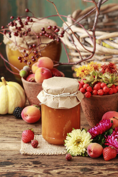 Jams in glass jars among fruits and vegetables.