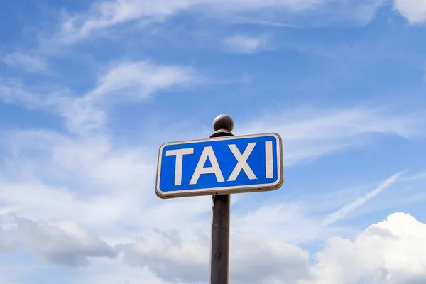 Taxi sign with blue sky background.