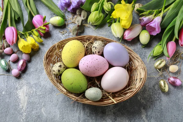 Basket of colorful Easter eggs on grey, stone background. — Stock Photo, Image