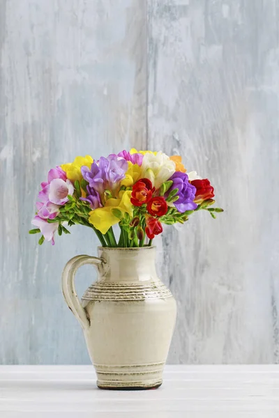 Boeket van kleurrijke Freesia bloemen in keramische vaas. — Stockfoto