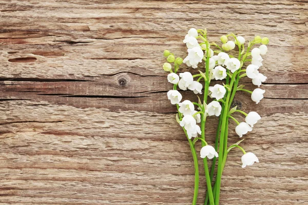 Lily kahverengi ahşap arka plan üzerinde vadi çiçekleri — Stok fotoğraf