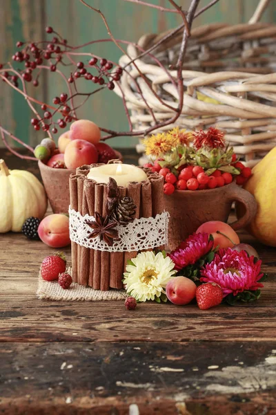 Candle decorated with cinnamon sticks among autumn fruits and fl — Stock Photo, Image