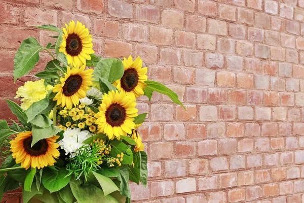 Bouquet of beautiful sunflowers on brick background