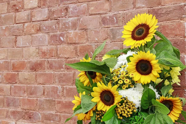 Bouquet of beautiful sunflowers on brick background