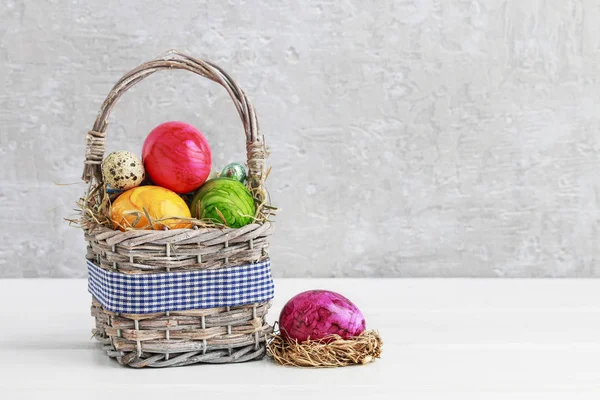 Colorful Easter eggs in wicker basket — Stock Photo, Image