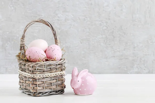 Wicker basket with Easter eggs and ceramic rabbit figure — Stock Photo, Image
