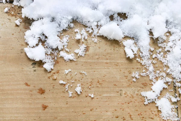 Real, natural snow melting on wooden background.