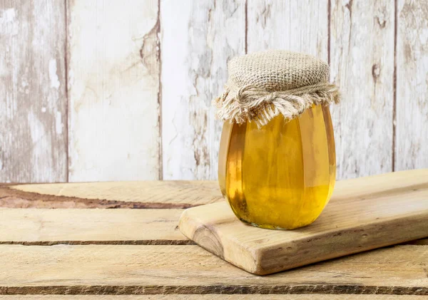 Madu dalam botol kaca pada latar belakang kayu — Stok Foto