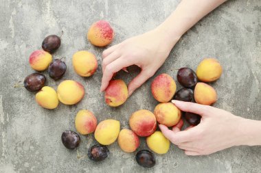 Şeftali ve erik tutan kadın, gri taş arka plan