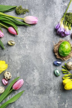 Renkli çiçekler ve gri, taş backgrou üzerinde paskalya yumurtaları boyalı