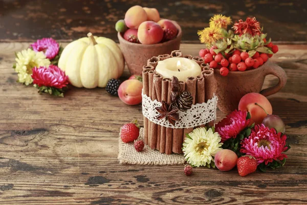 Candle decorated with cinnamon sticks among autumn fruits and fl — Stock Photo, Image