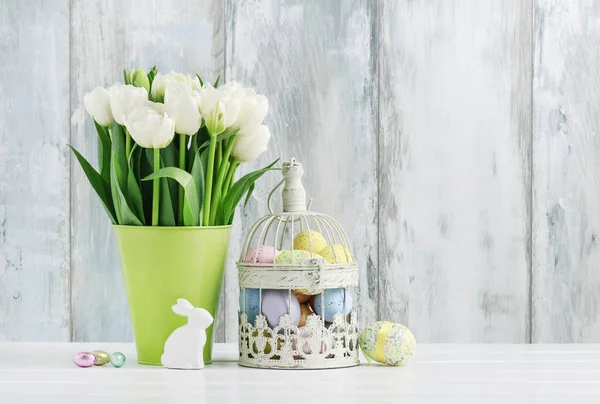 Gabbia per uccelli vintage piena di uova di Pasqua colorate e fiori primaverili — Foto Stock