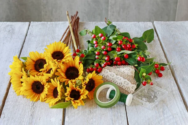 Wie man einen klassischen Strauß aus Sonnenblumen und Hypericum-Beeren macht, — Stockfoto