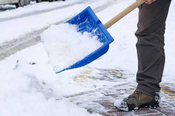 Человек убирает снег с тротуара после метели . — стоковое фото
