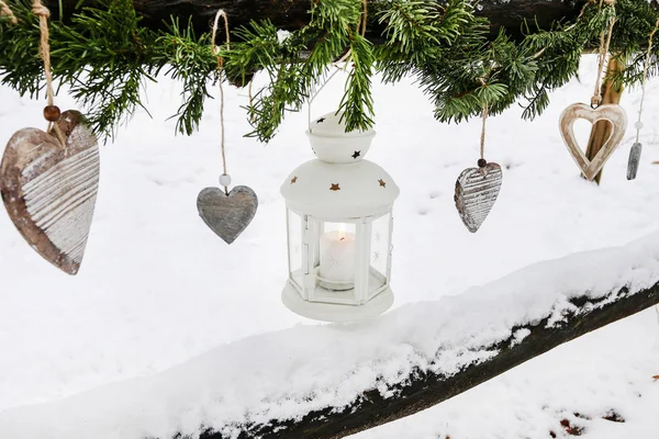 Grinalda de abeto, lanterna de ferro e corações de madeira pendurados no inverno ga — Fotografia de Stock