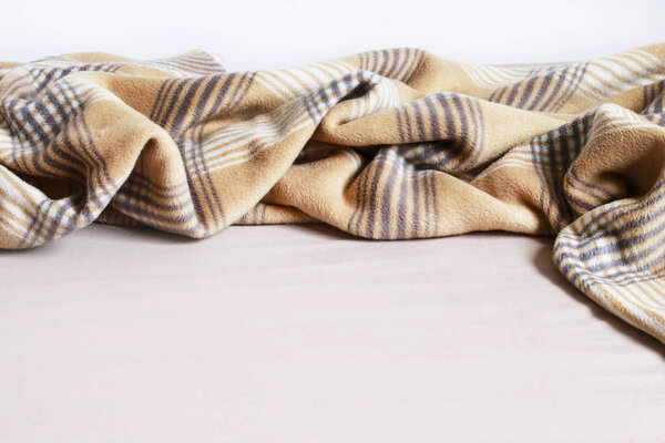 Beige blanket and bedsheet. 