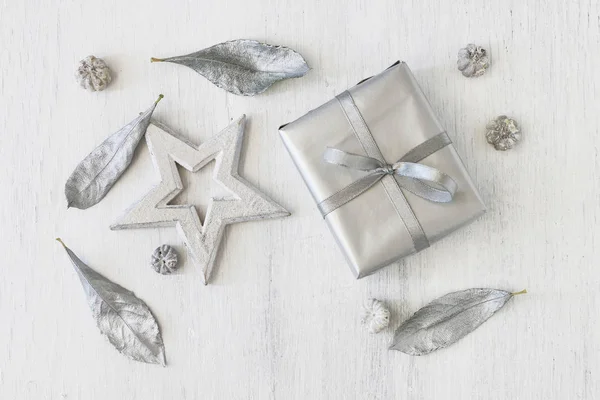 Foglie di stella, regalo e argento su sfondo bianco in legno — Foto Stock