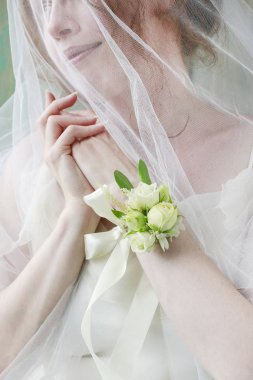 Gelin gül ve eustoma çiçekyapılmış bilek korsaj giyiyor. 