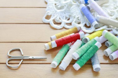 Ahşap masa üzerinde renkli iplikler ve güzel beyaz fransız dantel