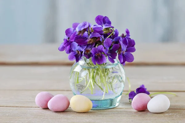 Boeket van kleine viooltjes (altviool odorata) en chocolade Easter Egg — Stockfoto