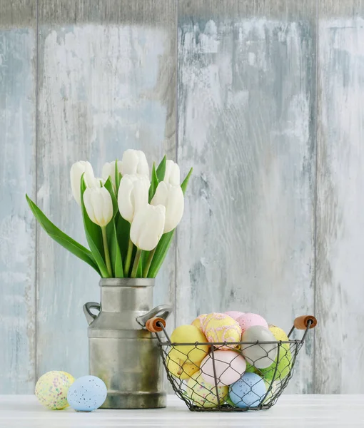 Cesto con uova di Pasqua e mazzo di tulipani bianchi in barattolo — Foto Stock