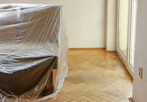 A couch covered with foil while painting the room. — Stock Photo, Image