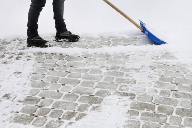 Kar fırtınası sonrası kaldırımdan kar kaldırma.