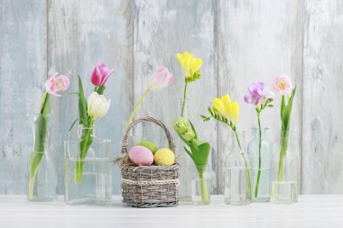 Cam şişelerde renkli çiçekler ve hasır güneşlikpaskalya yumurtaları
