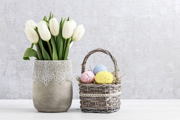 Bouquet di tulipani bianchi in vaso di ceramica e cesto di uovo di Pasqua — Foto Stock