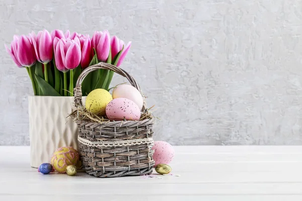 Strauß rosa Tulpen und Korb mit Ostereiern — Stockfoto