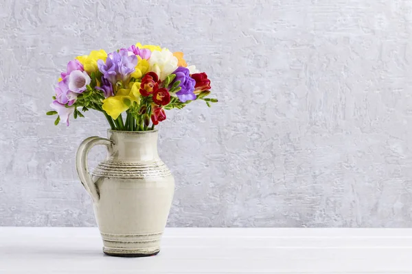 Букет з різнокольорових квітів фрезії в керамічній вазі — стокове фото