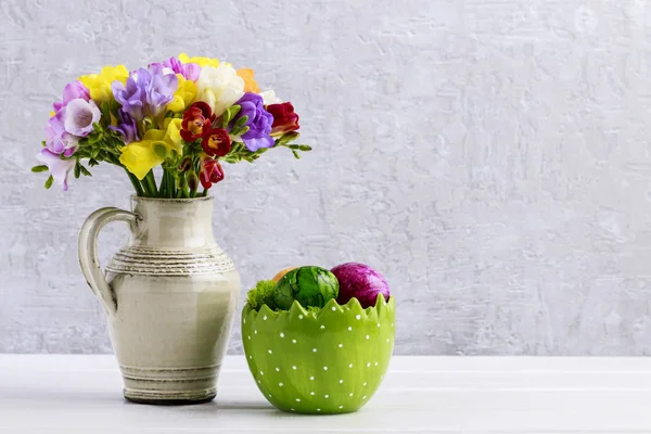 Bouquet of colorful freesia flowers in ceramic vase and Easter e — Stock Photo, Image