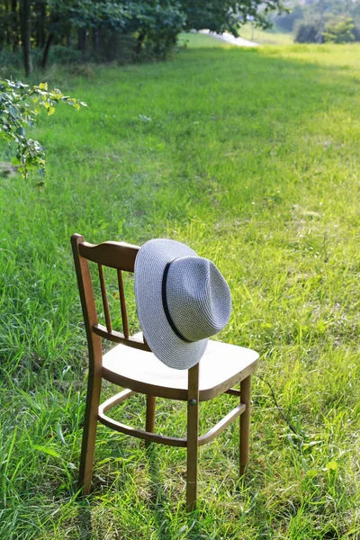 Drewniane krzesło i kapelusz w ogrodzie . — Zdjęcie stockowe