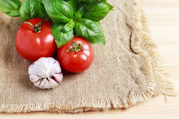 Tomates, ajo y albahaca sobre fondo de saco de yute . —  Fotos de Stock