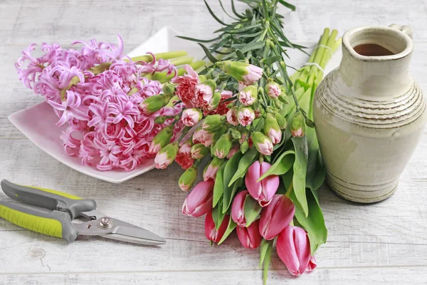 Woman shows how to make spring bouquet with tulip, hyacinth and — Stock Photo, Image