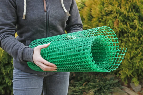 Женщина держит пластиковую сетку, которая полезна в садоводстве . — стоковое фото