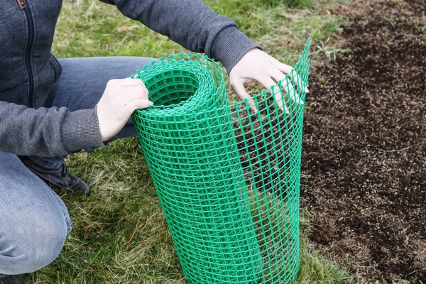 Bir kadın bahçe yararlı bir plastik ağ tutar. — Stok fotoğraf