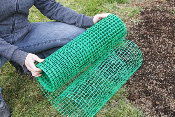 Eine Frau hält ein Plastiknetz in der Hand, das bei der Gartenarbeit nützlich ist. — Stockfoto