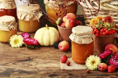 Meyve ve sebzeler arasında cam kavanozlarda reçeller.