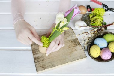 Kadın renkli e ile Paskalya çiçek dekorasyon yapmak için nasıl gösterir
