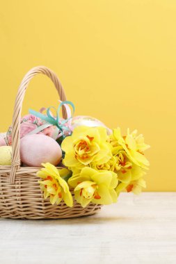 Paskalya yumurtaları ve nergis çiçekleriyle dolu hasır sepet.. 