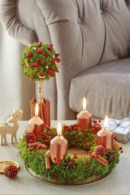 Yosun, tarçın çubukları ve rosa canina dalyapılmış Advent çelenk