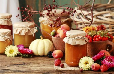 Meyve ve sebzeler arasında cam kavanozlarda reçeller.