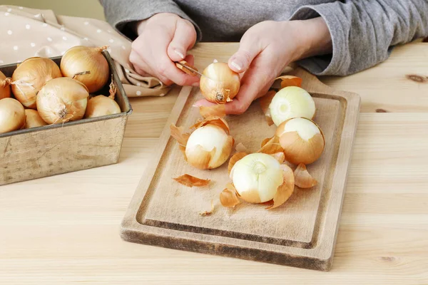Pelar cebollas en una tabla de madera . — Foto de Stock