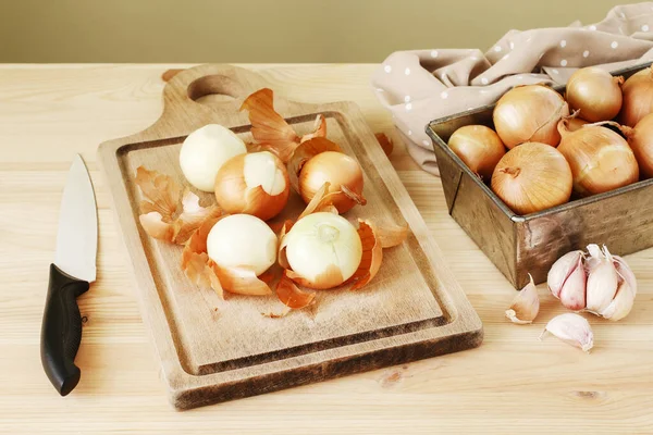 Peeling cipolle su una tavola di legno . — Foto Stock