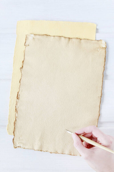 Hand with vintage pen and sheets of old paper. Woman writes a lo