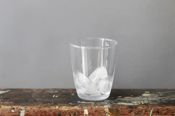 Ice cubes in a glass standing on a dirty table — Stock Photo, Image